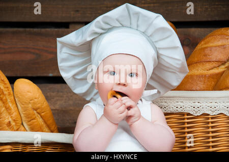 Porträt-Kind kocht im Hintergrund der Körbe mit Brötchen und Brot. Stockfoto