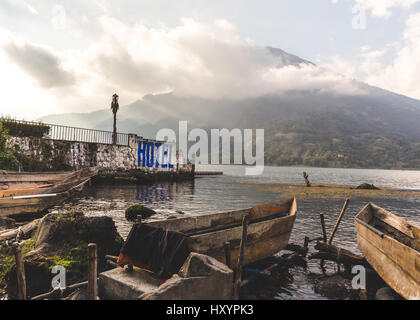 Bootsanlegestelle im Vordergrund und Cloud-bedeckten vulkanischen Berge in der Ferne am Lake Atitlan, Guatemala, Mittelamerika. Stockfoto