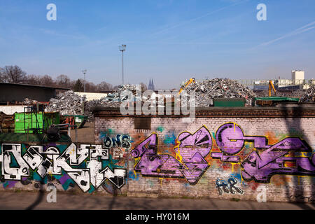 Deutschland, Köln, Schrott Hof mit alten Metall im Stadtteil Deutz, im Hintergrund die Kathedrale, Wand mit Graffiti. Stockfoto