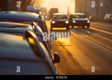 Straße in Stadt, Morgendämmerung mit parkenden Autos, zwei weiter verwischt mit beleuchteten Scheinwerfern auf die Straße, man pass (Kopie Raum) Stockfoto