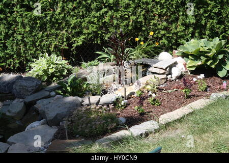 natürlicher Stein Wasserfall mit umliegenden Garten. Stockfoto