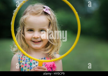 Young Bond Girl bläst einen riesigen Seifenblase Ring im Park Stockfoto