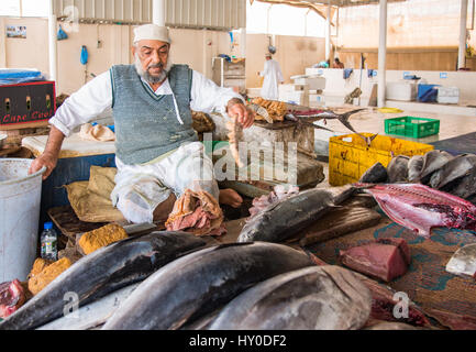 Anbieter auf dem Fischmarkt in Muscat, Oman, mit Gelbflossen-Thunfisch auf dem Tisch vor ihm. Stockfoto