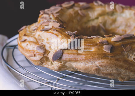 Frisch gebackene leckere Windbeutel mit Schokolade und gerösteten Mandeln auf einem Teller abkühlen bedeckt. Beliebtes Französisches Dessert. Stockfoto