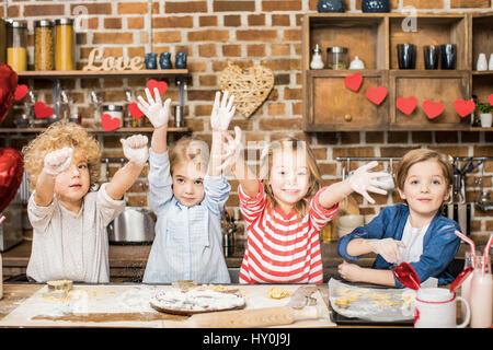 Entzückende glückliche Kinder kochen Kekse und Hände in Mehl Stockfoto