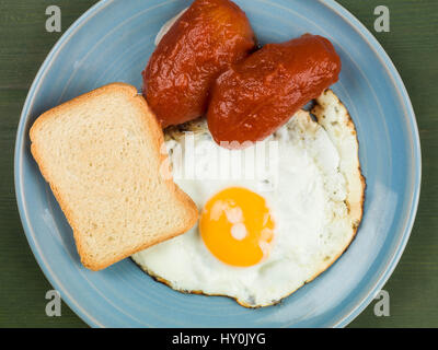 Spiegelei und Tomaten mit French Toast auf einen blauen Teller vor einem grünen Hintergrund Stockfoto