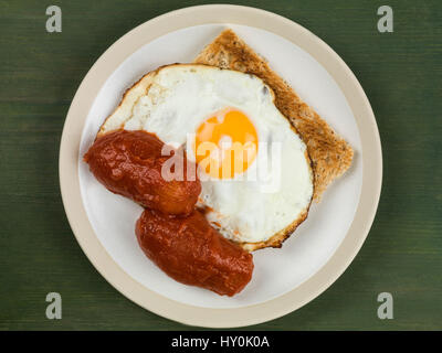 Spiegelei und Tomaten auf Toast auf einem Teller vor einem grünen Hintergrund Stockfoto