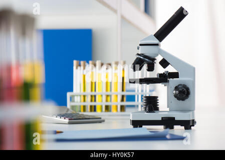 Mikroskop und Reagenzgläser auf Tisch im Labor Stockfoto