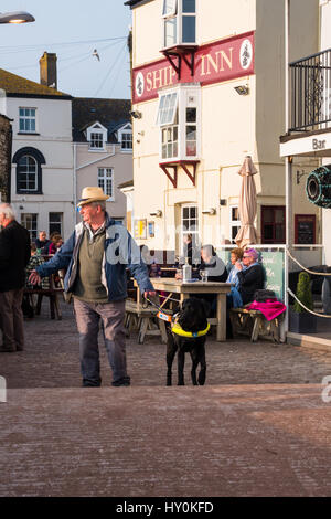 Mann und Blindenhund in Teignmouth, Großbritannien außerhalb der Ship Inn. Stockfoto