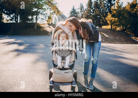 junge Mutter gehen mit ihrem baby und trägt sie in einem schönen Kinderwagen Stockfoto