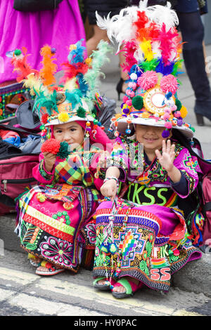 Bunte bolivianischen Kinder sitzen auf dem Bordstein in traditionellen Kostümen für die für St. Patricks Day parade London Stockfoto