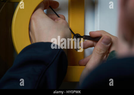 Einbrecher mit Lockpick Werkzeug öffnet die vordere Klappe, um das Haus zu betreten. Auch Schlüsseldienst oder Schlosser Stockfoto