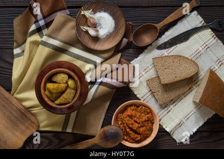 Gebackene Kartoffeln im Tontopf, Brot und sauce auf Holztisch Stockfoto