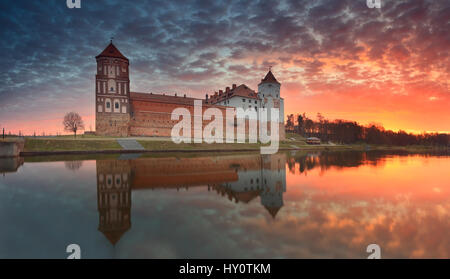 Burg am Sonnenaufgang Hintergrund spiegeln in See. Schönen Sonnenaufgang über dem See. Himmel weiße rot gelbe Wolken am Morgen. Stockfoto