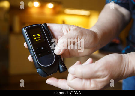 Hypoglykämischer Diabetiker testen ihr Blut für Blutzuckerspiegel zu Hause; niedriger Blutzucker. Medizinische Verfahren, Selbstdiagnose, gemeinsamen Stoffwechsel-, weit verbreitet Stockfoto