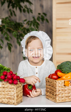 Gut aussehend Geißlein in uniform mit Gemüse Chef. Kochen in der Küche zu Hause. Vegetarier. Gesunde Ernährung Stockfoto