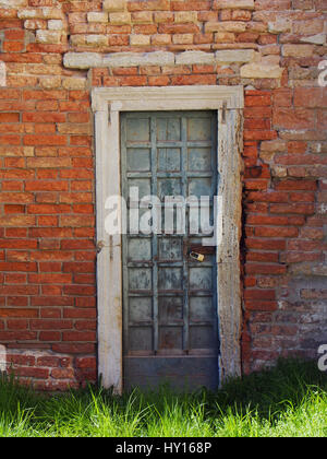 Grüne alte Holztür mit abblätternde Farbe und Rost Scharniere in einer alten Mauer Stockfoto