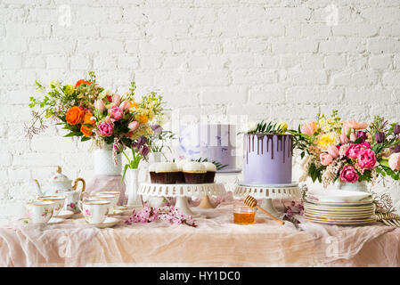 Sommer-Themen Desserttisch mit Muffins, Kuchen, Blumen und ein Tee-Set. Stockfoto
