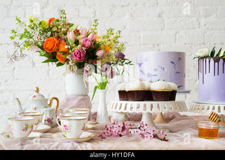 Horizontales Bild ein Tee-Set mit Muffins, Kuchen und einen Blumenstrauß. Stockfoto
