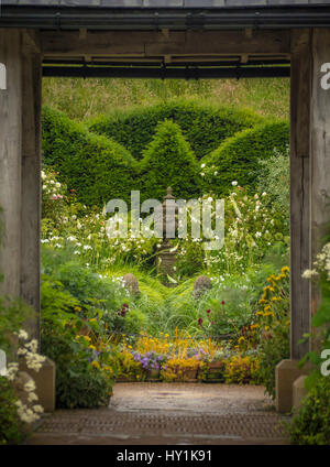 Formale gemischt Garten Pflanzen mit Formschnitt Absicherung durch hölzerne Struktur gesehen. Stockfoto