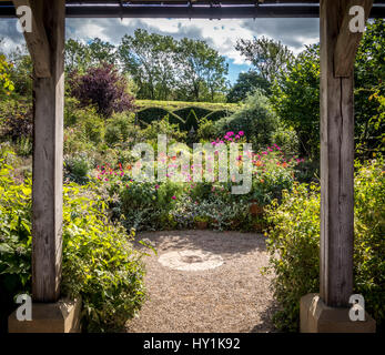 Formale gemischt Garten Pflanzen mit Formschnitt Absicherung durch hölzerne Struktur gesehen. Stockfoto