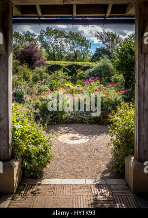 Formale gemischt Garten Pflanzen mit Formschnitt Absicherung durch hölzerne Struktur gesehen. Stockfoto