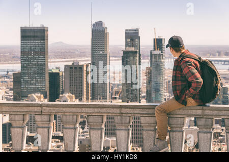 Montreal, CA - 30. März 2017: junger Mann sitzt auf der Brüstung und Blick auf die Skyline von Montreal aus Kondiaronk Belvedere Stockfoto