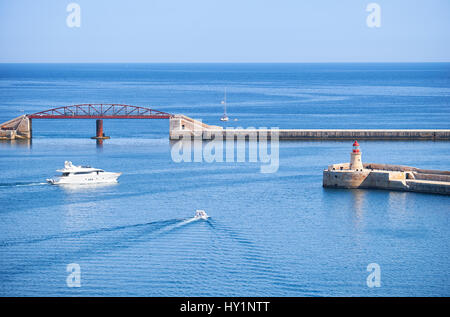 Zwei kleine Schiffe auf ihrem Weg aus Grand Hafen in der Nähe von The Ricasoli Leuchtturm und Mole Brückenneubau. Malta. Stockfoto