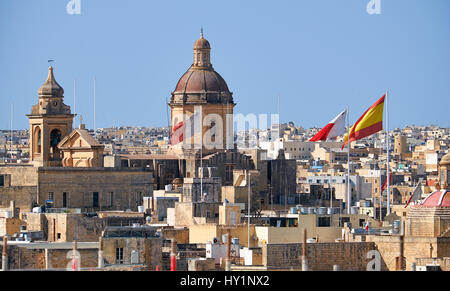 Der Blick auf die St. Lawrence Kirche umgeben von den Wohnhäusern mit Fahnen angehoben über den Urlaub, Birgu, Malta Stockfoto