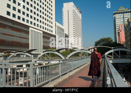 27.01.2017, Yangon, Republik der Union Myanmar, Asien - ein buddhistischer Mönch steht auf einer Fußgängerbrücke und nimmt Bilder der neuen sule Square. Stockfoto