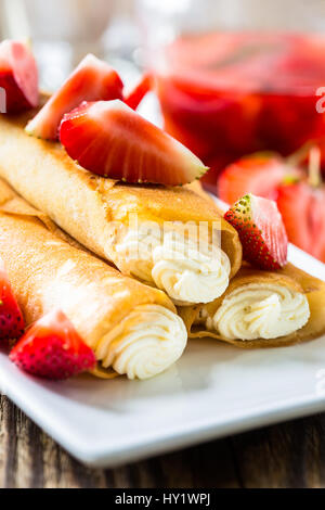 Crêpes gefüllt mit Käse und Erdbeer-Topping auf einem weißen Teller Stockfoto