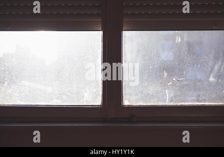 Blick aus dem Inneren auf schmutzigen Retro-Stil Fenster und helle Sonne mit einigen Formen außerhalb. Stockfoto