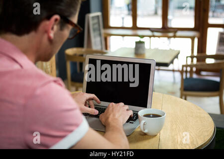 Rückansicht von Mann mit Laptop am Tisch im Café Stockfoto