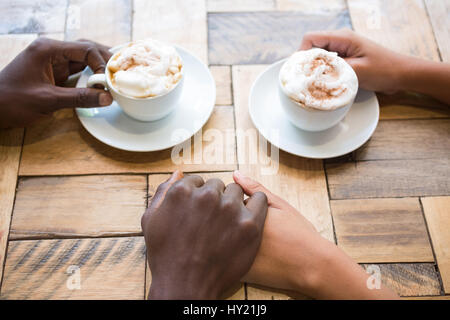 Erhöhte Ansicht des Paares Kaffeetrinken beim Händchenhalten im café Stockfoto