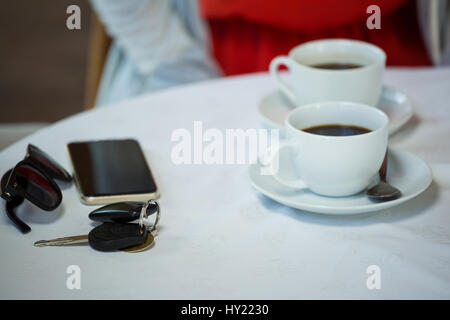 Vogelperspektive Blick auf Kaffeetassen und persönliche Accessoires am Café-Tisch Stockfoto