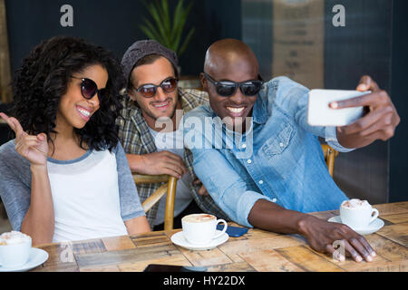 Fröhliche Multi ethnischen Freunde Sonnenbrille während der Einnahme von Selfie in Coffee-shop Stockfoto