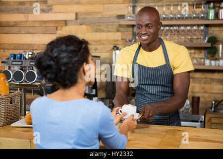 Glücklich männliche Barista Kaffee an Kunden im Coffee Shop serviert Stockfoto