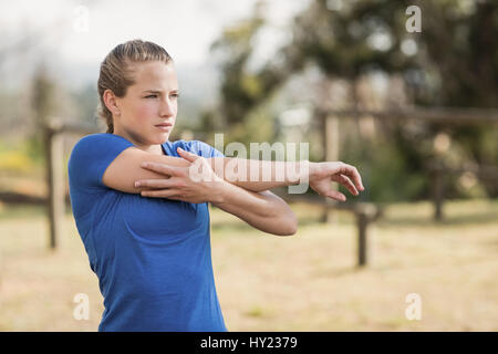 Fit Woman Dehnung Ausübung während der Hindernis-Parcours mit Boot Camp ausführen Stockfoto