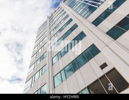 Hohes Gebäude oder Skyscraper gegen blauen Wolkenhimmel. Wolken reflektieren im Fenster des Gebäudes. Stockfoto