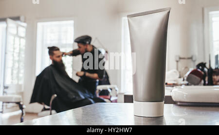 Rasierschaum Rohr auf Theke mit Barber Client im Hintergrund dienen. Stockfoto