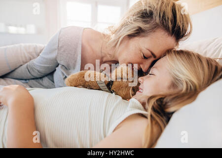 Niedliche kleine Mädchen mit ihrer Mutter am Bett liegen. Mutter und Tochter zu Hause miteinander schlafen. Stockfoto