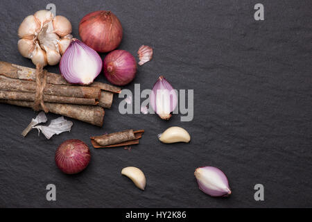 Kochen Zutaten: Zimtstangen und Knoblauch auf schwarz Tisch aus Stein. Stockfoto