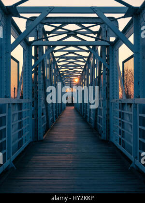 Symmetrie-Ansicht der Fußgängerbrücke über die Bahnstrecke bei Sonnenuntergang. Leeren Raum. Stockfoto