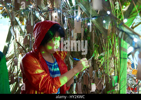 Frau trägt einen roten Mantel unterhalb der Wunsch Baum, Green Man-Festival, Wales Stockfoto