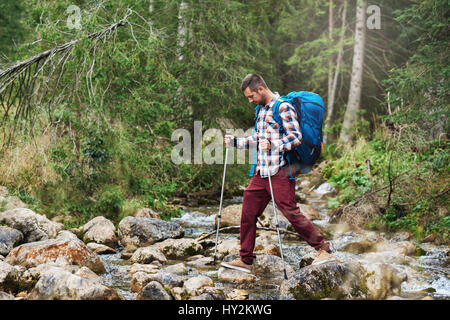 Wanderer, die Überquerung eines Flusses im Wald Stockfoto