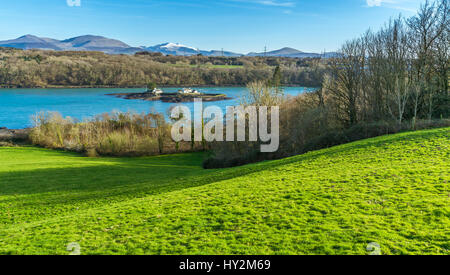 Ein Blick über die Menaistraße von einem Aussichtspunkt auf Anglesey, mit den Snowdonia-Bergen im Hintergrund Stockfoto