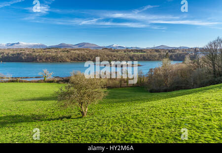 Ein Blick über die Menaistraße von einem Aussichtspunkt auf Anglesey, mit den Snowdonia-Bergen im Hintergrund Stockfoto