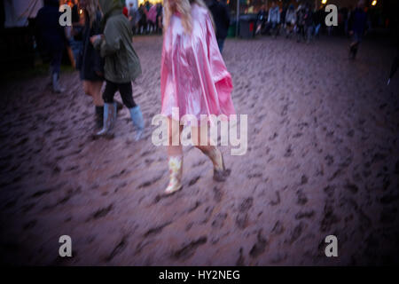 Frau trägt einen rosa Poncho geht durch den Schlamm auf dem Grren Mann Festival, Wales Stockfoto