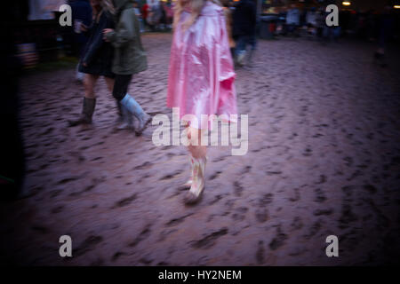 Frau trägt einen rosa Poncho geht durch den Schlamm auf dem Grren Mann Festival, Wales Stockfoto