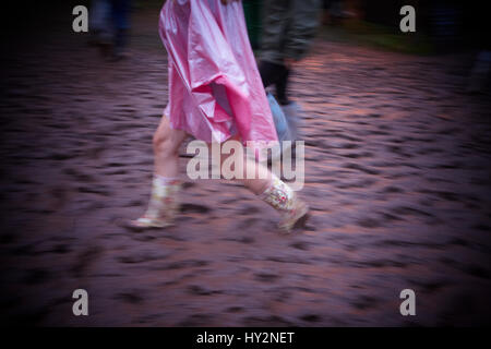 Frau trägt einen rosa Poncho geht durch den Schlamm auf dem Grren Mann Festival, Wales Stockfoto